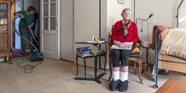 Oudere vrouw zittend op een stoel in haar kamer