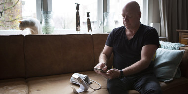 Man in zijn huiskamer verstuurt gegevens van bloeddrukmeting