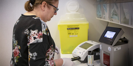 Praktijkondersteuner voert urinetest uit met behulp van een analyser