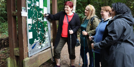 vrouwelijke wandelgroep bij een plattegrond in het bos