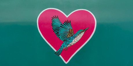 Schilderij van een rood hart waar een blauwgroene vogel voor vliegt