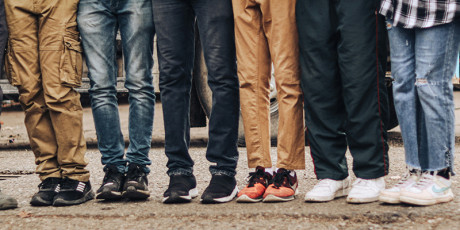 Voeten en benen van verschillende jongeren staand naast elkaar