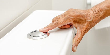Hand bij een wc-pot, klaar om door te trekken