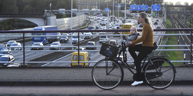 Vrouw met kind fiets op een viaduct over de snelweg