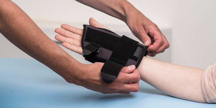 Twee handen die een handschoen aantrekken bij een derde hand.